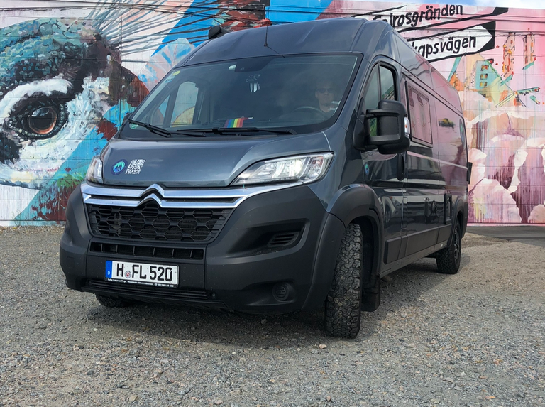 Van von vorne im Hintergrund eine Graffiti Wand.