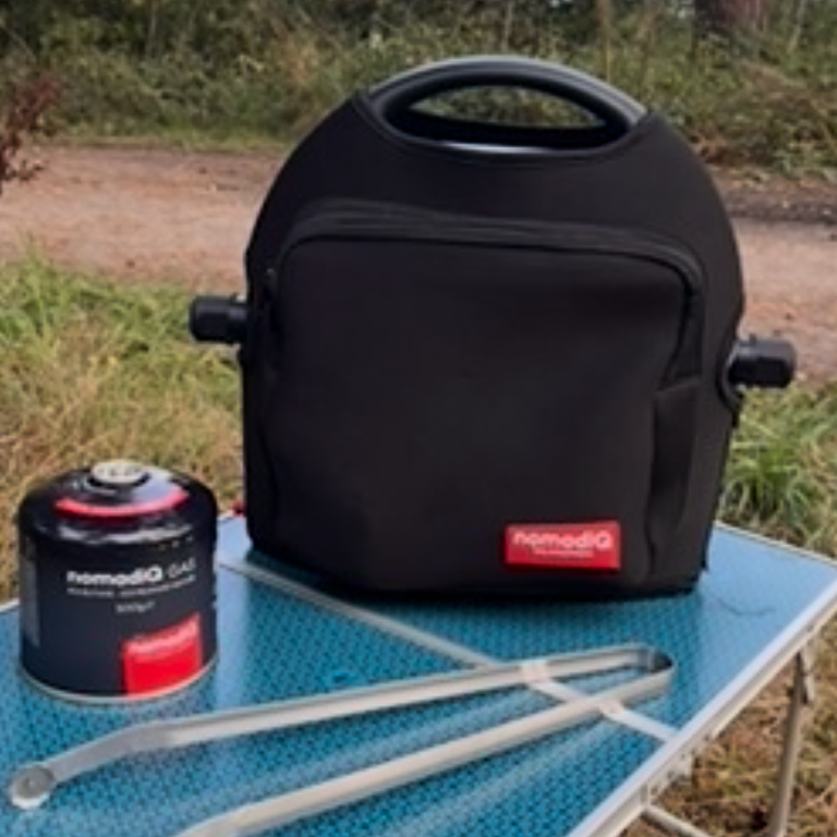 nomadiQ BBQ mit Tragetasche auf einem Campingtisch