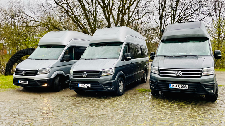 Drei Grand California 600 nebeneinander auf einem Waldparkplatz