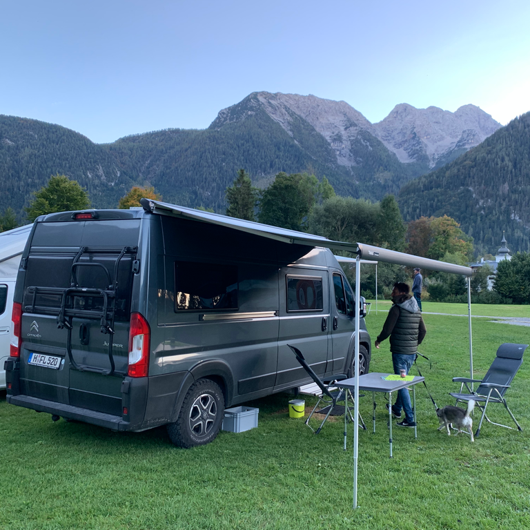 Pössl Summit mit ausgefahrener Markise, Campingmöbeln und Nick im Hintergrund
