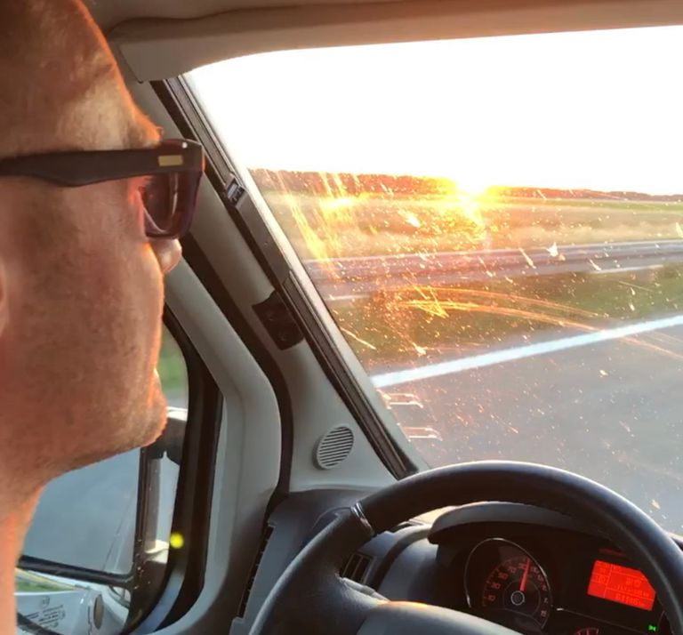 Marco beim Fahren mit Sonnenbrille. Die Sonne steht tief und geht gleich unter.